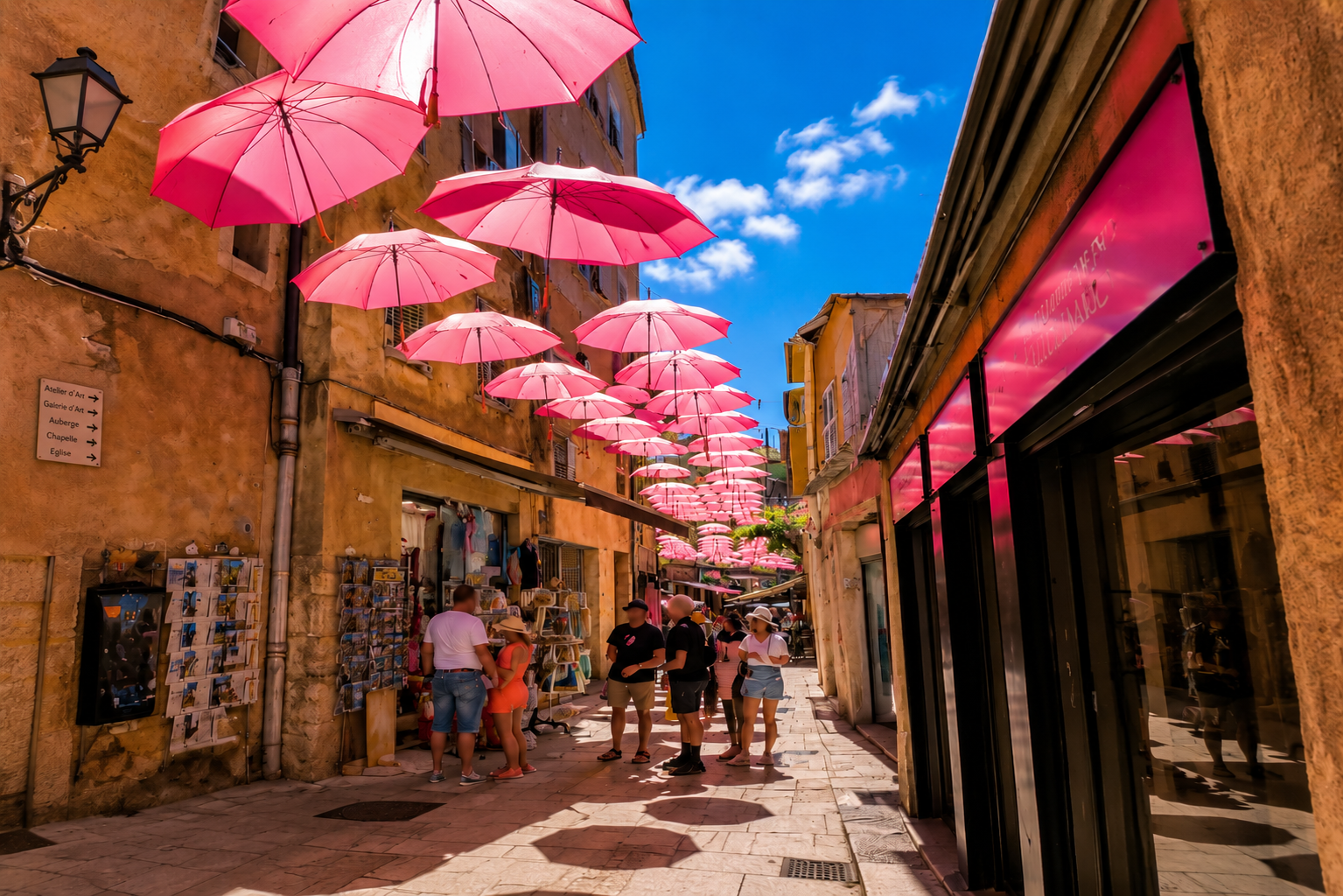 Ruelle de Béziers décorée d'ombrelles roses en été